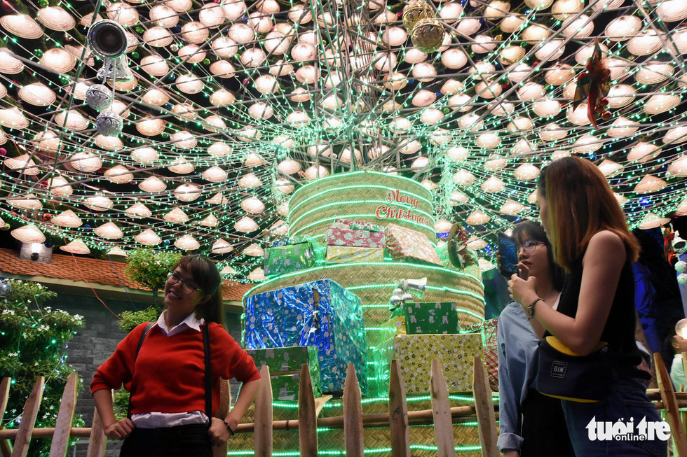 Visitors pose for photos with the 20-meter Christmas tree made up of 1,200 non la in the southern province of Dong Nai. Photo: Tuoi Tre