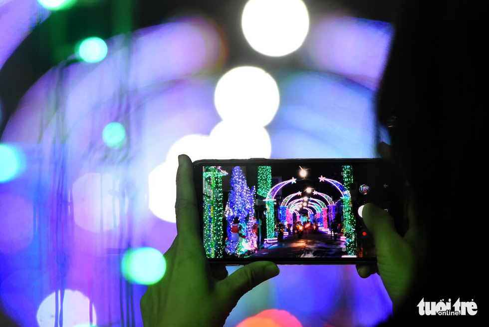 A visitor takes a photo of a street lightened up with decorative lights in the southern province of Dong Nai. Photo: Tuoi Tre