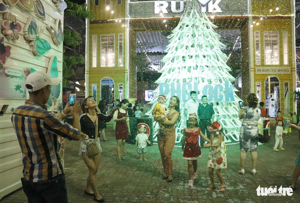 Visitors pose for photos with the 8-meter Christmas tree made up of 200 plastic chairs at the Rubik Zoo in Ho Chi Minh City. Photo: Tuoi Tre