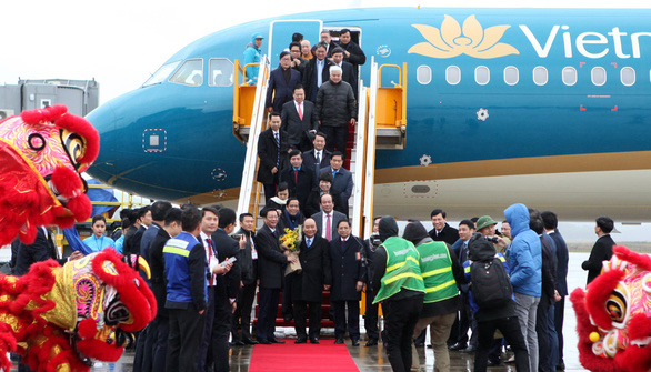 PM Nguyen Xuan Phuc (central) holds a bunch of flowers as he arrived on the first commercial flight, operated by Vietnam Airlines, to land at Van Don International Airport, December 30, 2018. Photo: Tuoi Tre