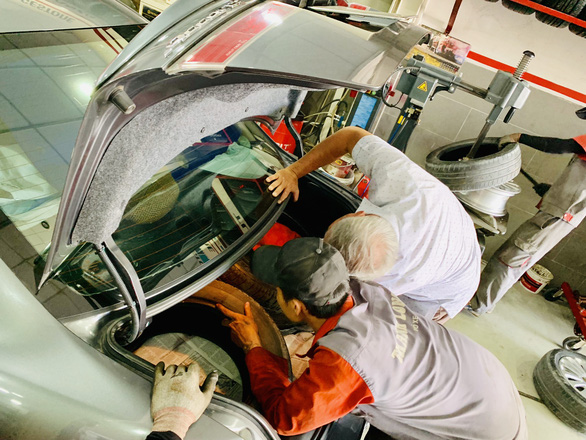 Employee and owner checks a car before maintenance at an establishment. Photo: Cong Trung / Tuoi Tre