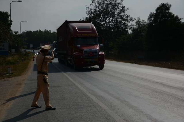 An officer pulls a tractor trailer over at a police checkpoint in Binh Thuan Province, Vietnam. Photo: Duc Trong / Tuoi Tre
