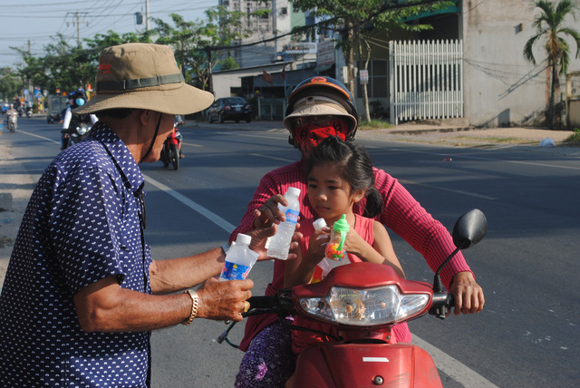 Nguyen Van Thanh gives a bottle of drinking water to a woman on a road in Dong Thap Province, southern Vietnam, January 30, 2019. Photo: Thanh Nhon / Tuoi Tre
