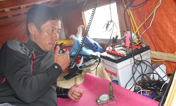 A man uses a telecommunication device on a bamboo raft. Photo: Truong Trung / Tuoi Tre 