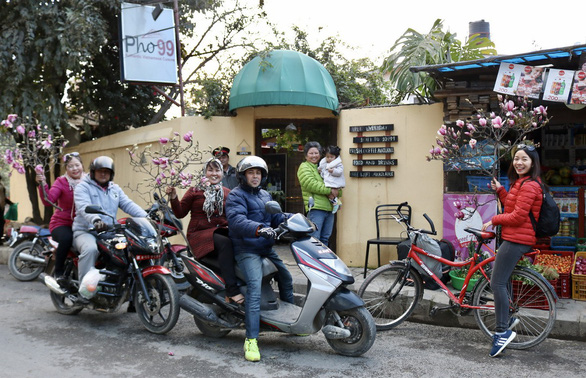 Huong Xuan (right) buys a branch of magnolias to decorate her house for Tet. Photo: Hiep Tran