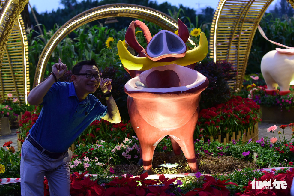 A sightseer poses for a picture near a pig statue. Quang Dinh / Tuoi Tre