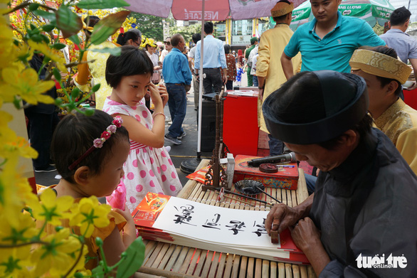  Young kids watch a calligrapher perform. Photo: Tuyet Kieu / Tuoi Tre