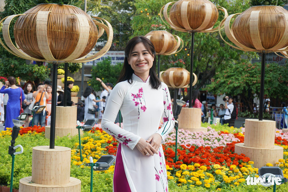  A woman dressed in ‘ao dai’ poses for a photo at the flower street. Photo: Tuyet Kieu / Tuoi Tre