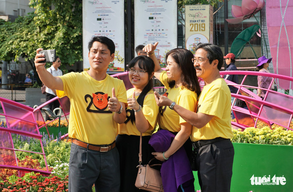  People take a group photo along Nguyen Hue Flower Street. Photo: Tuyet Kieu / Tuoi Tre