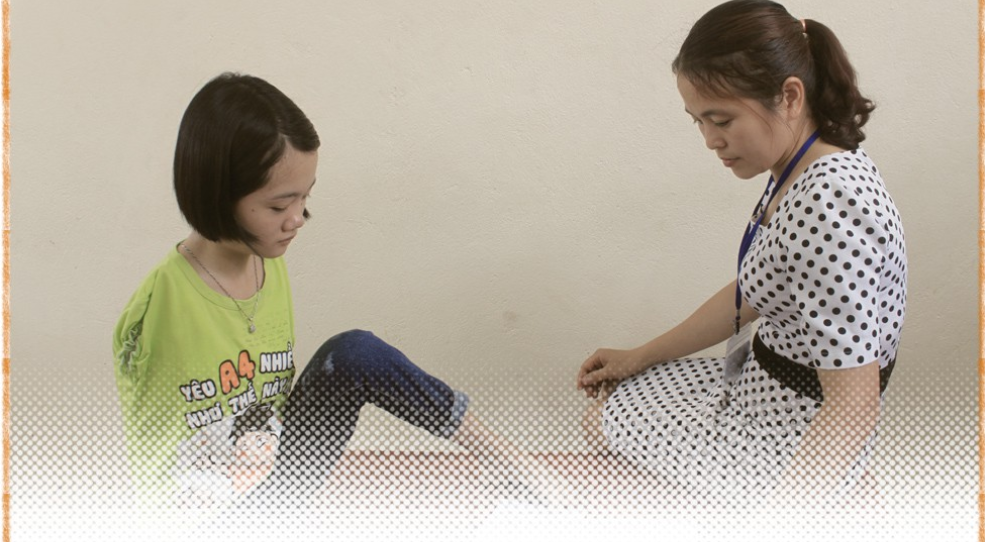Le Thi Tham (left) learns to write. Photo: Le Kien / Tuoi Tre