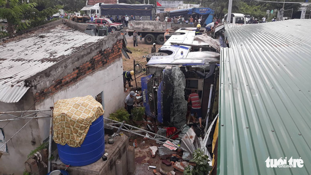 An overturned passenger bus lies next to house rubble after one of its tires goes flat in Nha Trang City, south-central Vietnam, February 14, 2019. Photo: Dinh Cuong / Tuoi Tre