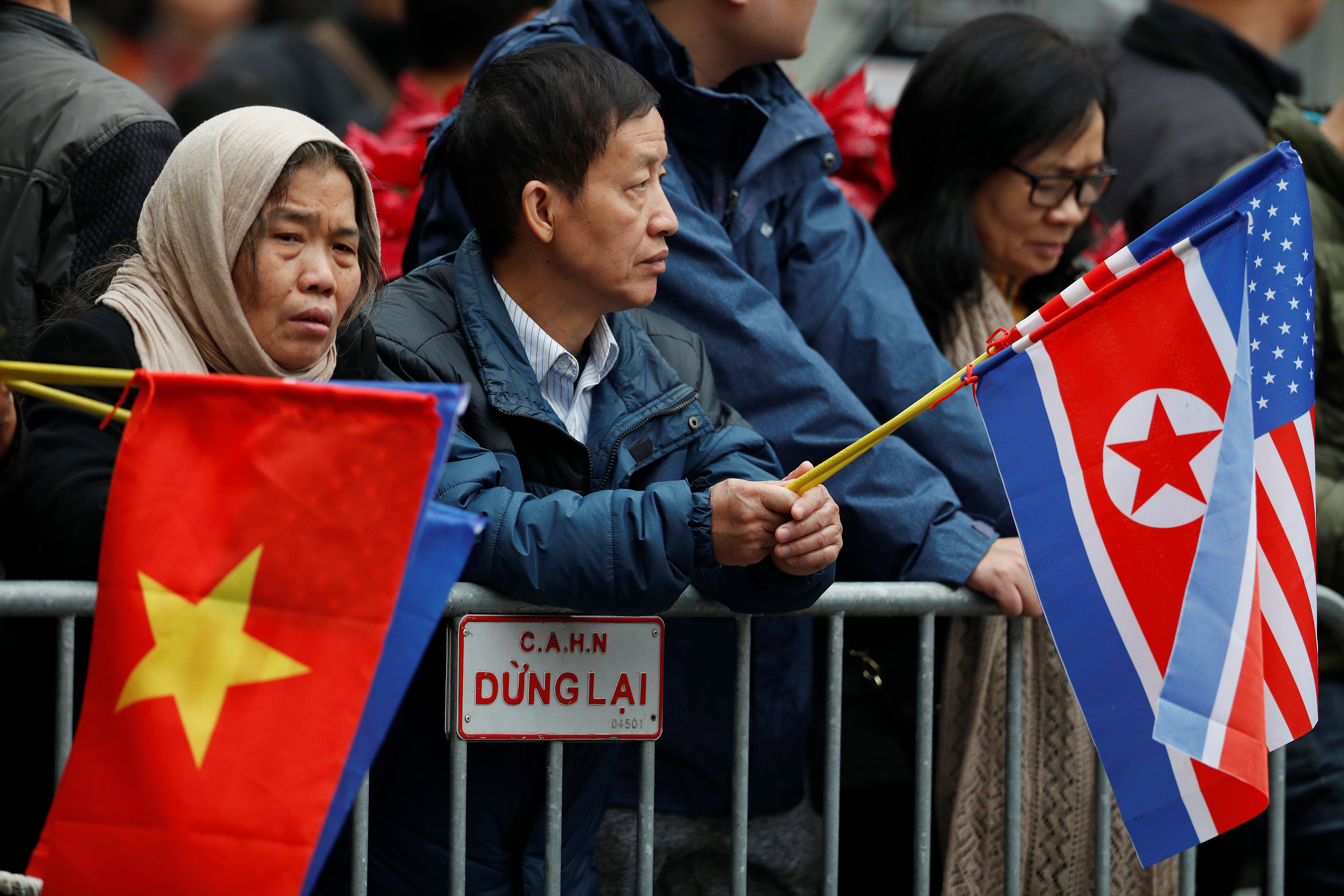 People hold the national flags of Vietnam, North Korea, and the U.S. as they wait for the motorcade of North Korean leader Kim Jong Un outside the Melia hotel ahead of the North Korea-U.S. summit in Hanoi, Vietnam February 26, 2019.  Photo: Reuters