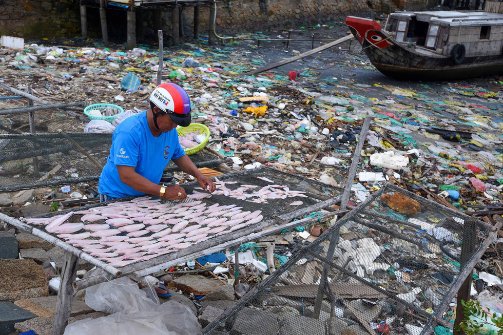 A resident dries fish on a trash-filled beach in Can Gio District, Ho Chi Minh City.