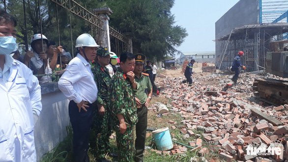 A government official and police watch the effort to find laborers in the rubble of collapsed wall in Vinh Long Province, southern Vietnam, March 15, 2019. Photo: Thanh Nam / Tuoi Tre