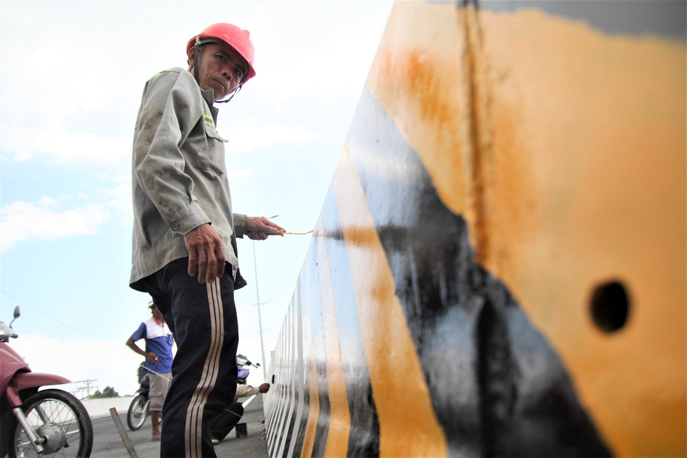 A construction worker paints the median strip along the structure.