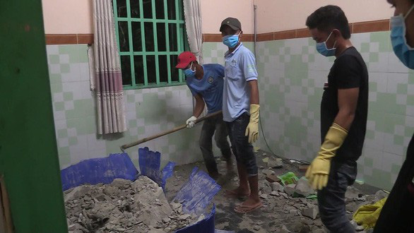 People break the concrete-filled barrel to retrieve the body. Photo: Ba Son / Tuoi Tre
