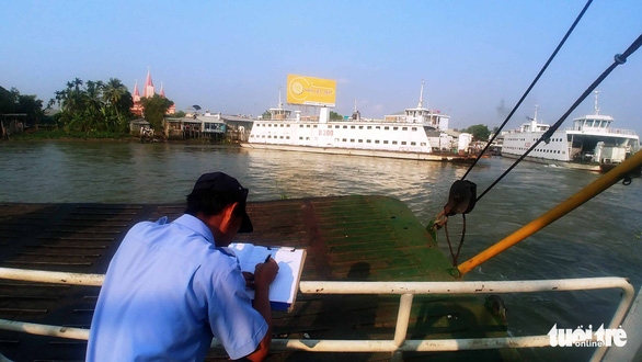 A worker writes about the Vam Cong ferry crossing in a diary. Photo: Mau Truong / Tuoi Tre