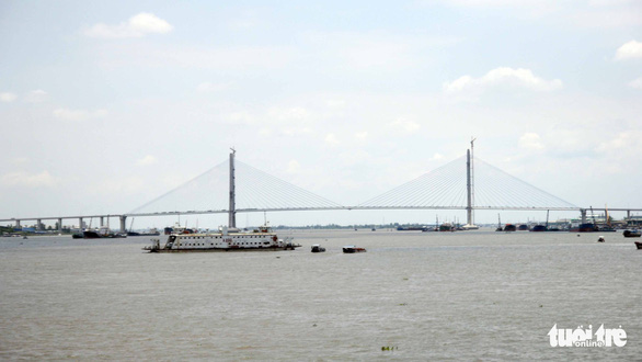 A Vam Cong ferry carries passengers across Hau River, with the bridge to replace it seen in the background, Photo: Mau Truong / Tuoi Tre