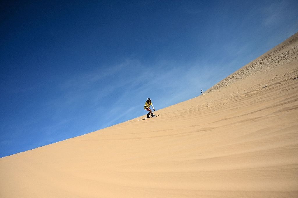 Sun-kissed and shaggy haired, Nguyen Thai Binh swaps his flip flops for bulky boots ahead of snowboarding practice on the sand dunes of southern Vietnam -- the unlikely training ground for the country's fledgling winter athletes. Photo: AFP