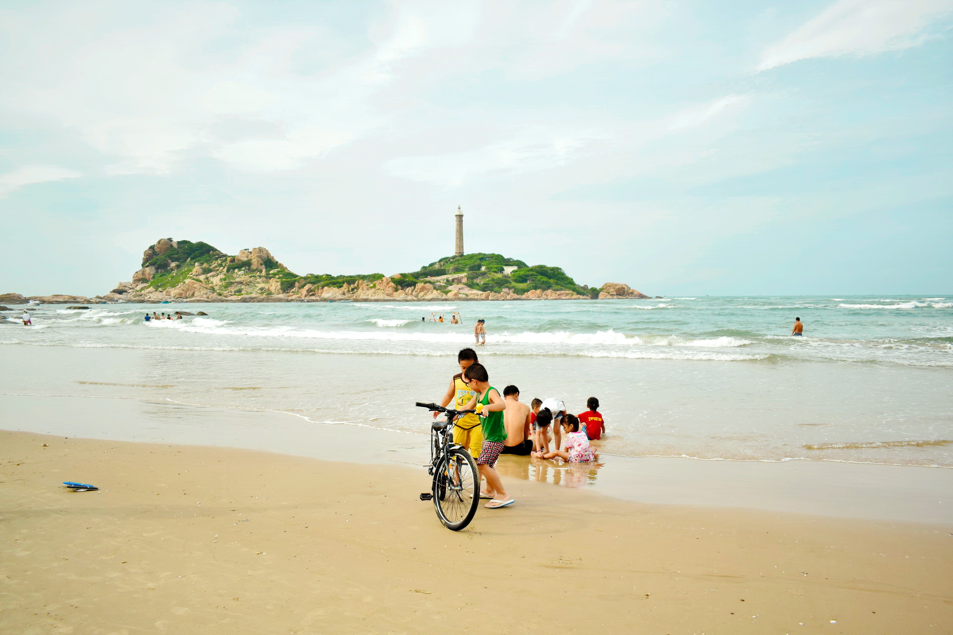 Beach-goers take a swim in the water at the Ke Ga Beach in Binh Thuan Province, Vietnam as the Ke Ga Lighthouse is seen in the background. Photo: Tuan Son / Tuoi Tre News