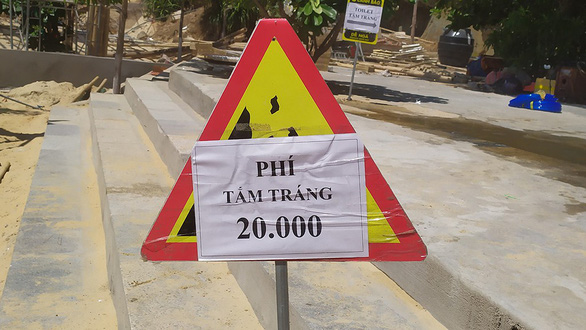 An A4-size paper informs visitors about the price of taking freshwater shower after swim at Ky Co Beach in Binh Dinh Province, south-central Vietnam. Photo: Ba Quyen / Tuoi Tre