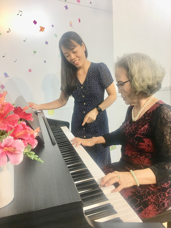 Nguyen Thi Lam, 80, learns to play the piano under careful instructions of the teacher. Photo: My Lang / Tuoi Tre