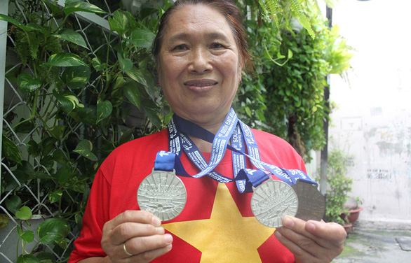 Tang Duy Ngoc holds two medals for swimming and smiles in pride. Photo: Tuoi Tre