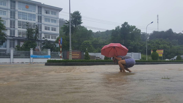 A resident struggles to walk on a flooded street. Photo: Van Tien / Tuoi Tre