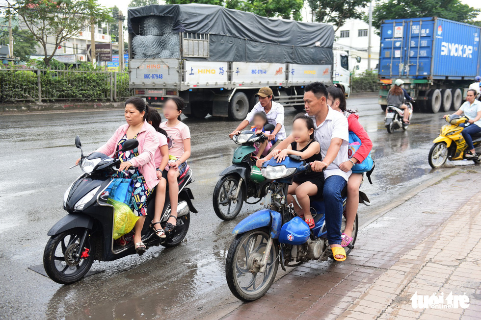 Parents and children wearing no helmet travel wrong way on a section of National Highway 1 passing through District 12, Ho Chi Minh City. Photo: Quang Dinh / Tuoi Tre