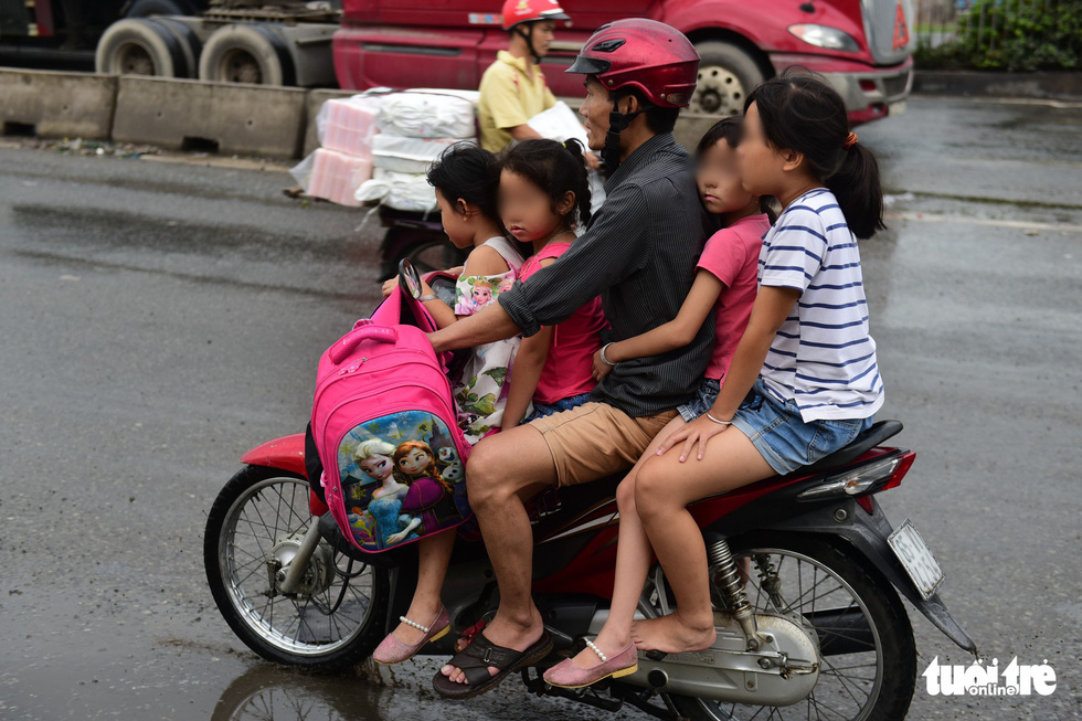 A man carries four children, who wear no helmet, on one vehicle in Ho Chi Minh City. Photo: Quang Dinh / Tuoi Tre