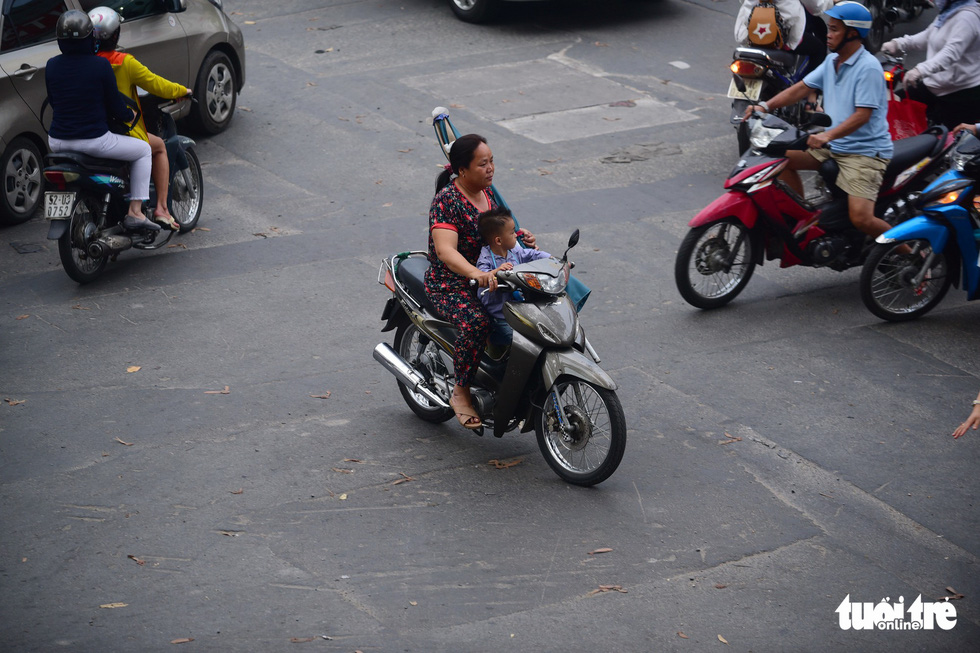 A woman carries her child on a street in Ho Chi Minh City, wearing no helmet. Photo: Quang Dinh / Tuoi Tre