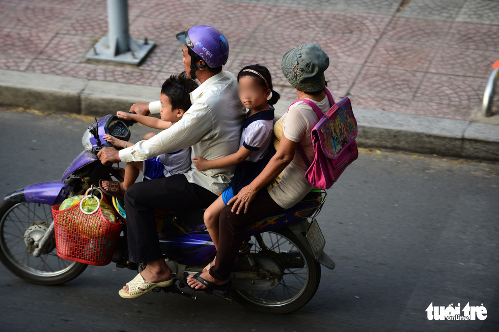 Parents wear helmets, while their children don’t on a street in Ho Chi Minh City. Photo: Quang Dinh / Tuoi Tre