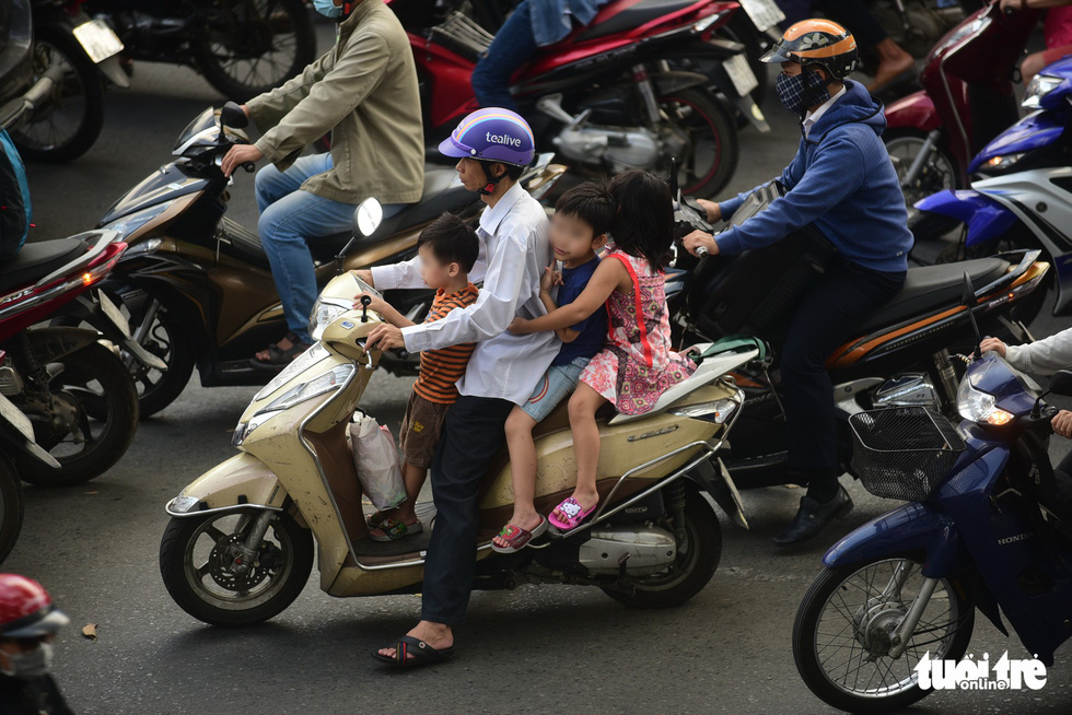 A man carries three children, who wear no helmet, on one vehicle in Ho Chi Minh City. Photo: Quang Dinh / Tuoi Tre