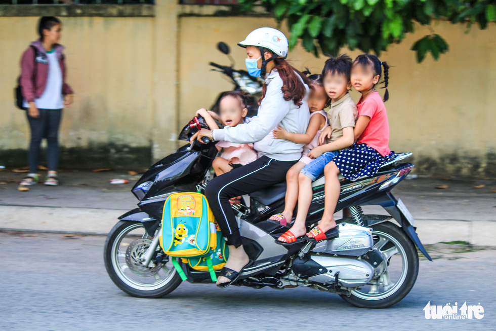 A woman carries four children, who wear no helmet, on one vehicle in Ho Chi Minh City. Photo: Quang Dinh / Tuoi Tre