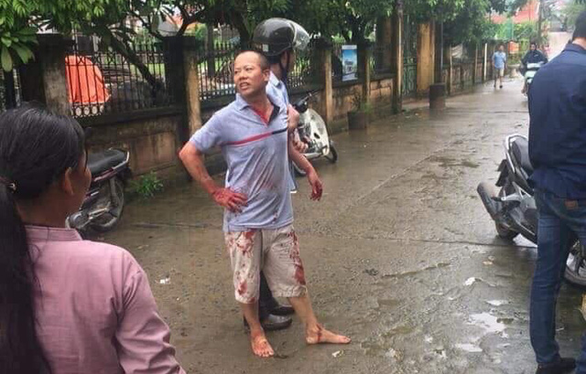 Nguyen Van Dong is seen being held by an officer after killing four members of his brother's family in Hanoi on September 1, 2019. Photo: Tuoi Tre