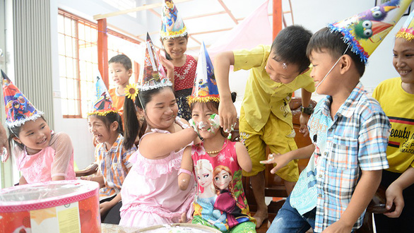 Hieu Thao (middle) and Hoai Thuong (on her left) smile happily in Thao’s birthday party. Photo: Tu Trung / Tuoi Tre