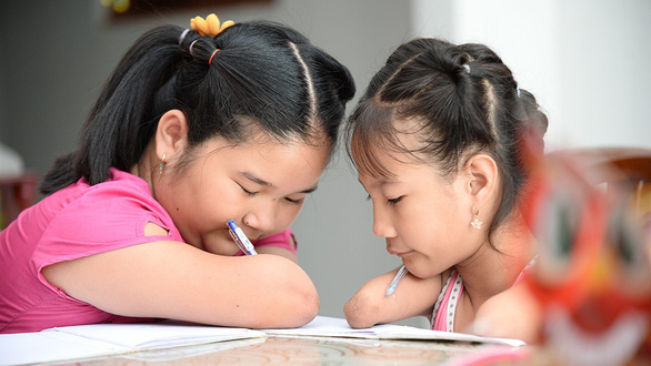 Hoai Thuong (left) teaches Hieu Thao to write by pens in this photo taken in Soc Trang, southern Vietnam. Photo: Tu Trung / Tuoi Tre