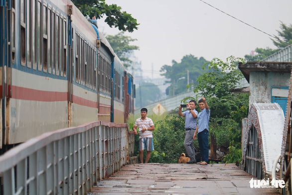 Local people film the last train passing the old Binh Loi Railway Bridge. Photo: Ngoc Phuong / Tuoi Tre