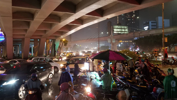 Commuters wait under an overpass for the rain to stop. Photo: Chau Tuan / Tuoi Tre