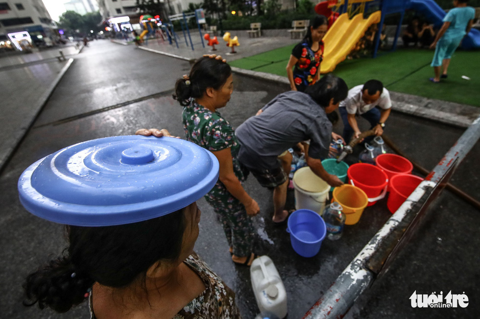 People queue for clean water in the rain in Hanoi. Photo: Nguyen Khanh / Tuoi Tre