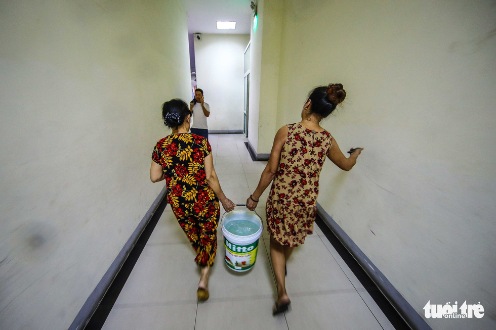 Two women carry a bucket of fresh water back to their apartment in Hanoi. Photo: Nguyen Khanh / Tuoi Tre