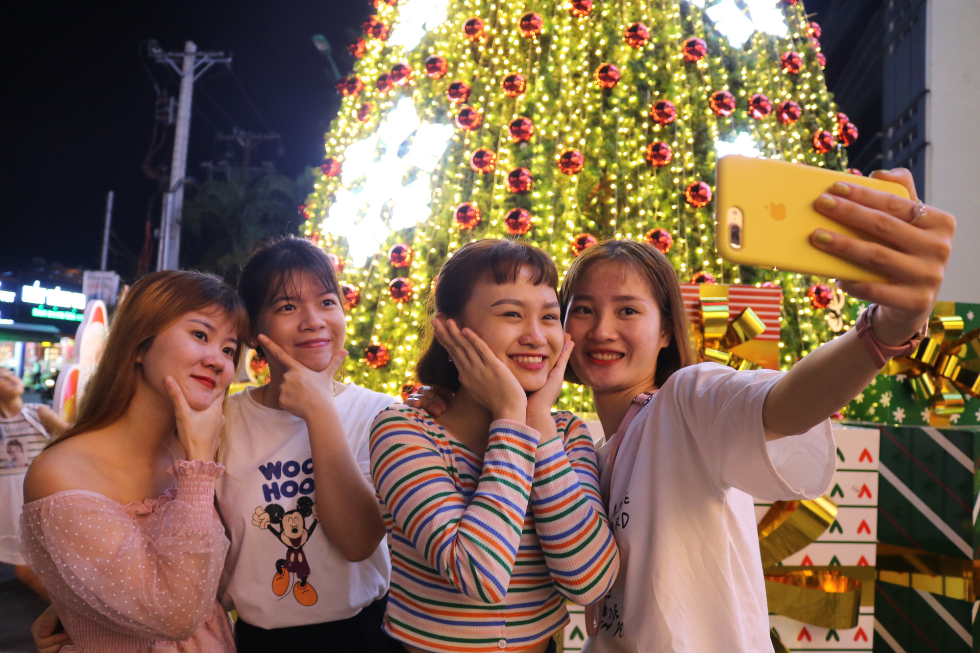 Young girls take a photo with the giant Christmas tree at Landmark 81 Tower. Photo: Hoang An / Tuoi Tre