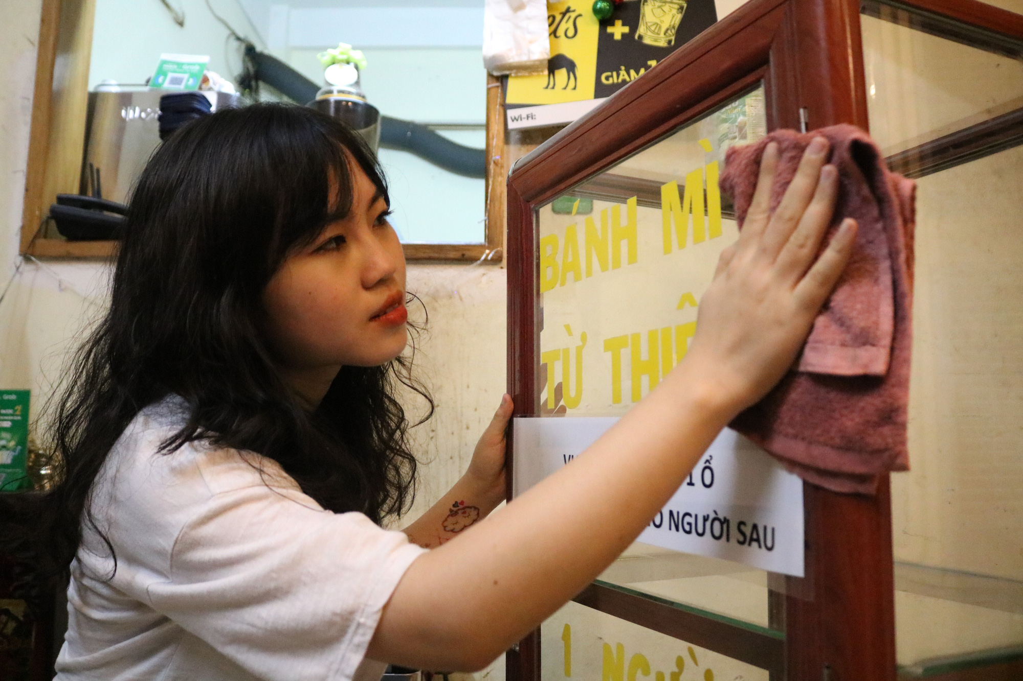 College student Nguyen Thi My Dung cleans a container which she uses to store free bread for those in need in Ho Chi Minh City. Photo: Ngoc Phuong / Tuoi Tre