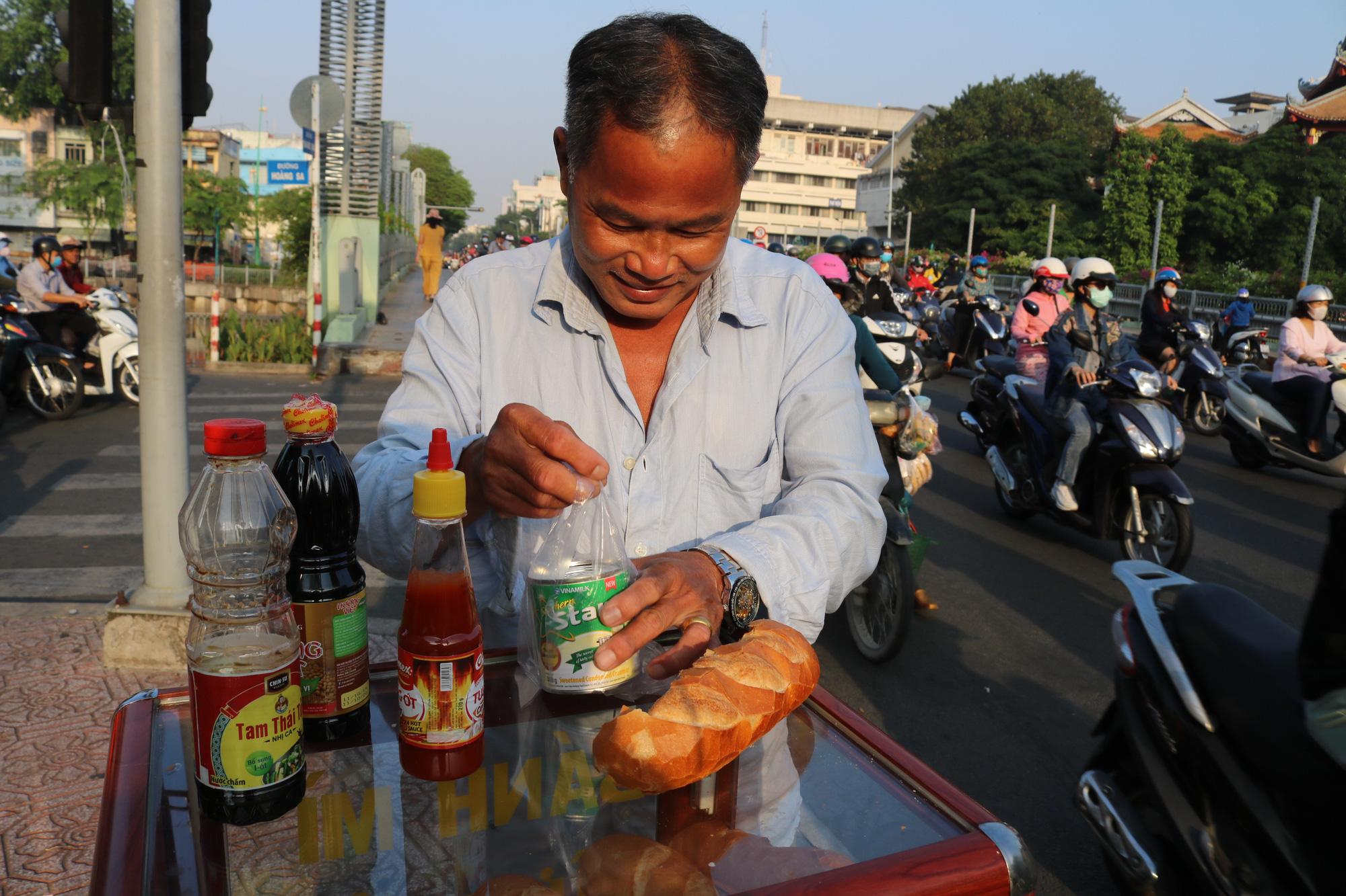 A man restocks condensed milk at a charity bread box donated by college student Nguyen Thi My Dung in Ho Chi Minh City. Photo: Ngoc Phuong / Tuoi Tre