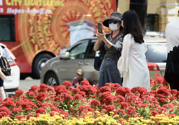 A woman is seen wearing face mask while taking photos with outdoor Tet (Vietnamese Lunar New Year) decorations in Ho Chi Minh City. Photo: Tuoi Tre/Tu Trung
