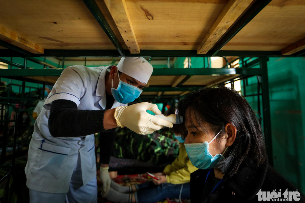 A medical staff checks the body temperature of a woman at the Military School of Lao Cai Province in northern Vietnam. Photo: Nguyen Khanh / Tuoi Tre