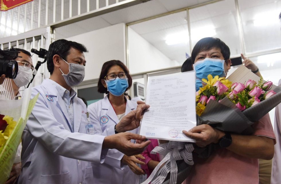 Li Ding (R) receives a certificate of discharge from Nguyen Tri Thuc, director of Cho Ray Hospital in Ho Chi Minh City, Vietnam, February 12, 2020. Photo: Duyen Phan / Tuoi Tre