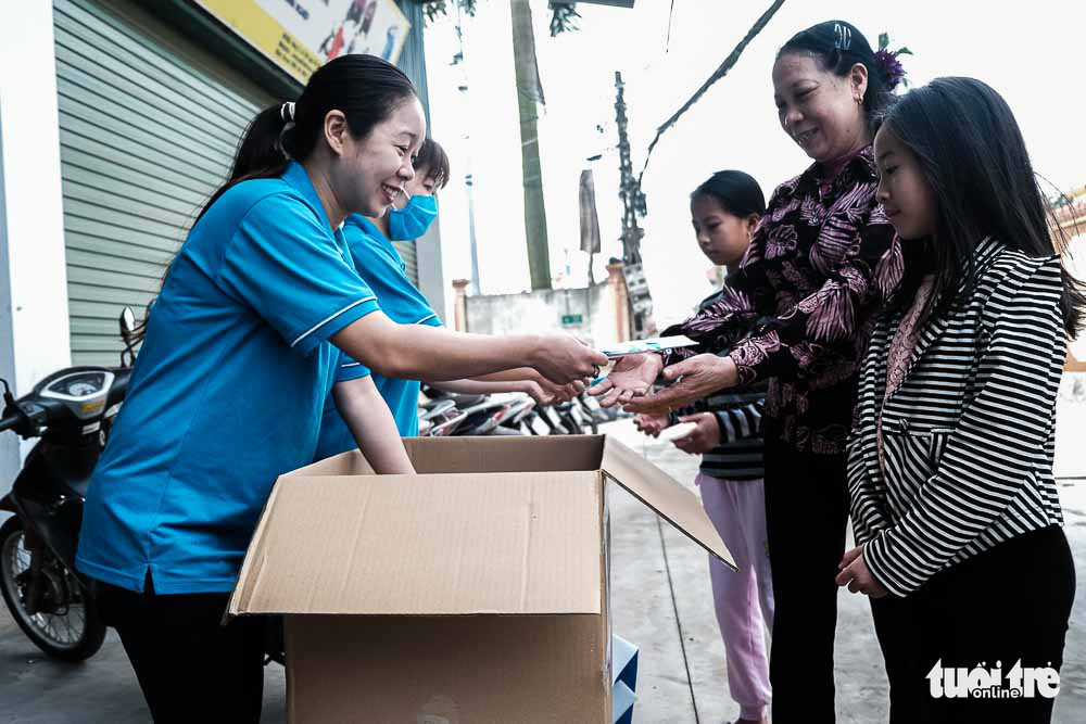 Le Thi Tham gives away free face masks outside her raincoat factory in Dong Anh District, Hanoi, Vietnam. Photo: Mai Thuong / Tuoi Tre