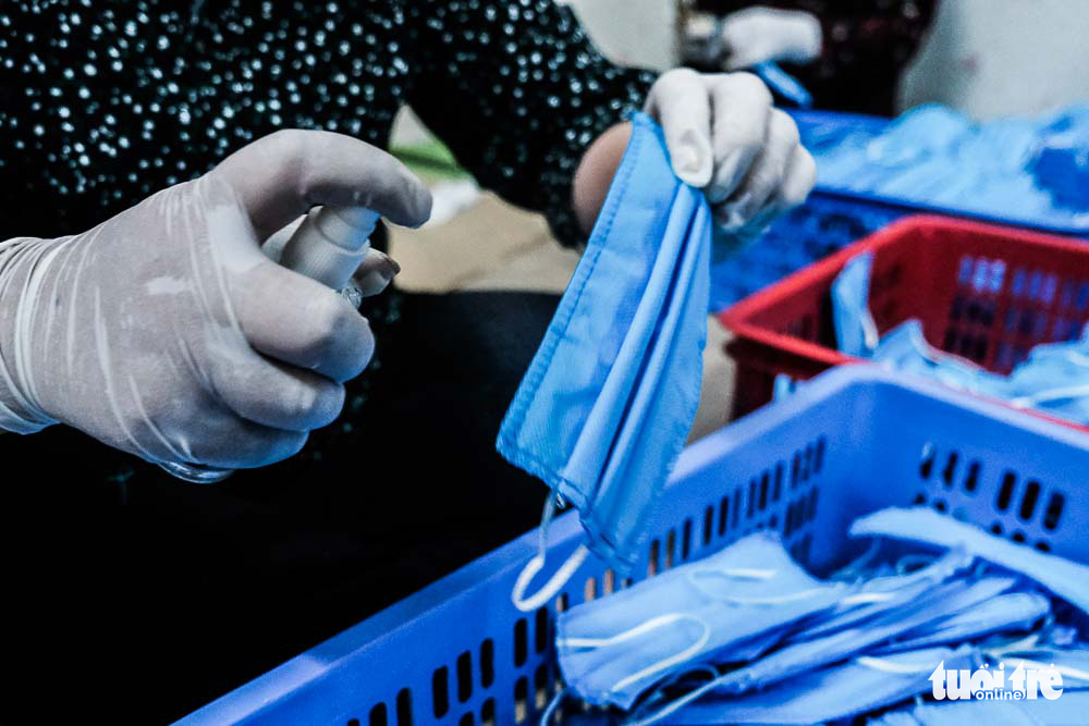 A member of Hai Boi Women’s Union helps sterilize face masks at a raincoat factory in Dong Anh District, Hanoi, Vietnam. Photo: Mai Thuong / Tuoi Tre
