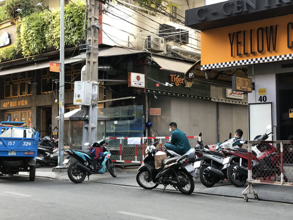Militia officers guard alley No. 40 on Bui Vien Street, District 1, Ho Chi Minh City as a COVID-19 patient once stayed there. Photo: Le Phan / Tuoi Tre 